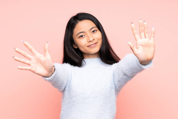 Teenager-Chinesin auf rosa Hintergrund isoliert und zählt mit den Fingern zehn - Foto, Bild