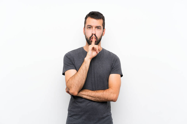 Mladý pohledný muž přes izolované bílé pozadí ukazující znamení mlčení gesto dát prst do úst - Fotografie, Obrázek