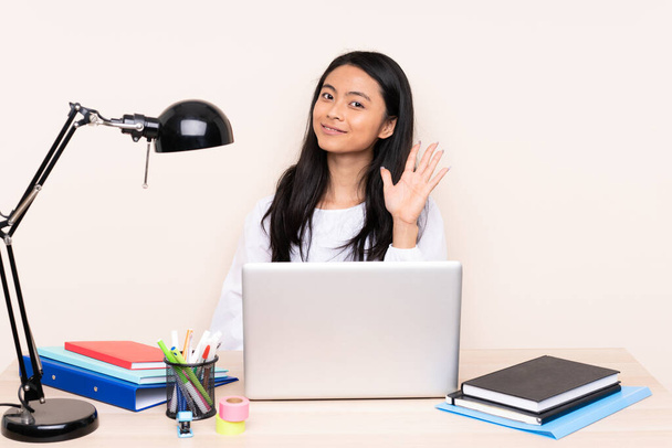 Student asian girl in a workplace with a laptop isolated on beige background counting five with fingers - Photo, Image