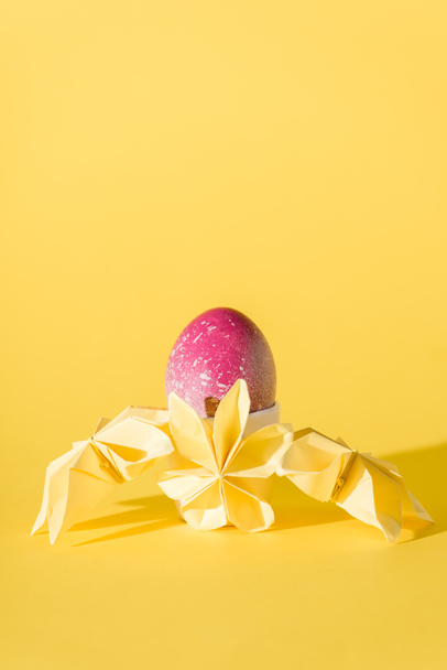 paper flowers near painted easter egg on yellow with copy space  - Photo, Image