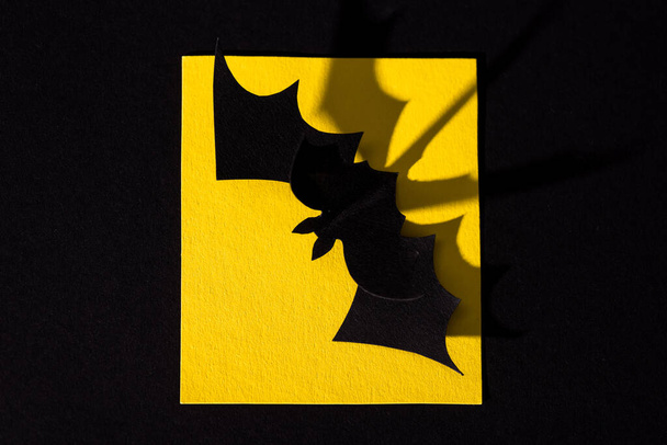 top view of origami bat on yellow paper isolated on black  - Zdjęcie, obraz