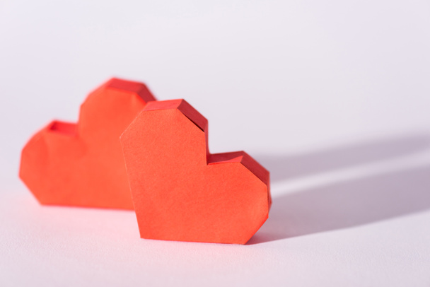 selectieve focus van rode origami hartjes op wit met kopieerruimte  - Foto, afbeelding