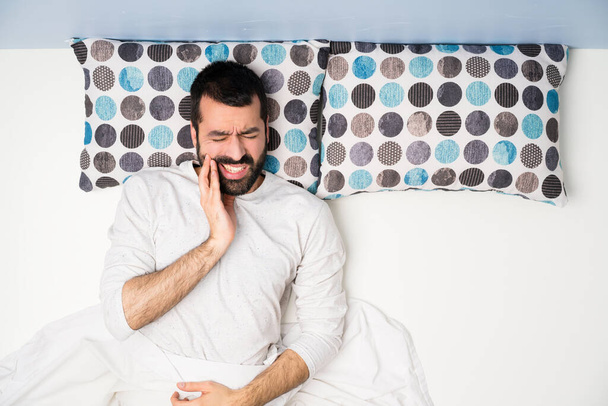 Homem na cama em vista superior com dor de dente
 - Foto, Imagem