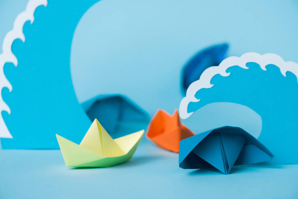selective focus of colorful paper ships near waves on blue  - Fotografie, Obrázek