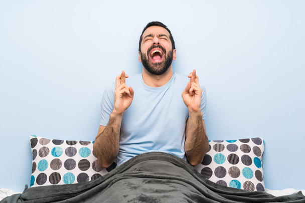 Чоловік в ліжку з пальцями перетинаючи
 - Фото, зображення