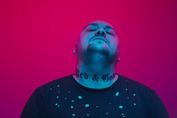 Portrait of a guy with colorful neon light on red background - cyberpunk concept - 写真・画像