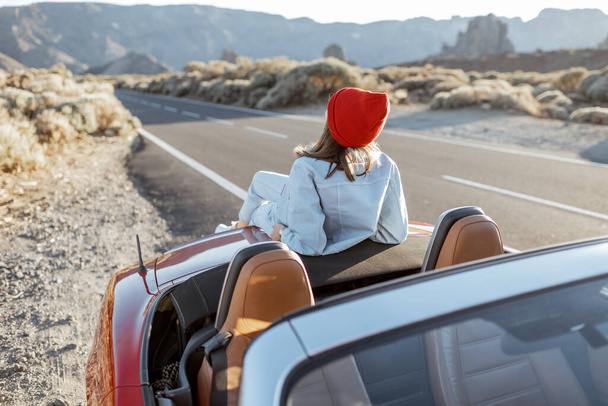 Woman traveling by car on a desert valley - 写真・画像
