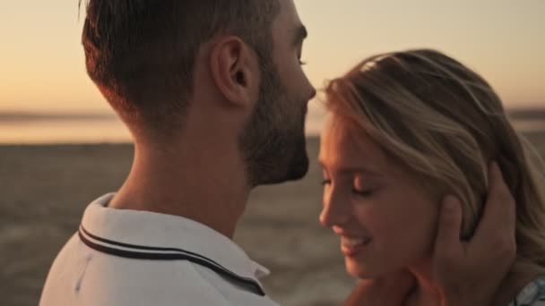 Atraktivní pár se navzájem obdivují, zatímco mají rande na slunné pláži v blízkosti jezera - Záběry, video