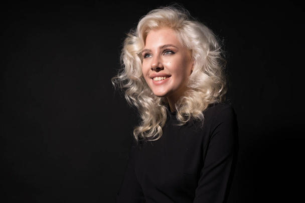 Heureuse blonde bouclée femme souriant isolé sur fond noir
 - Photo, image