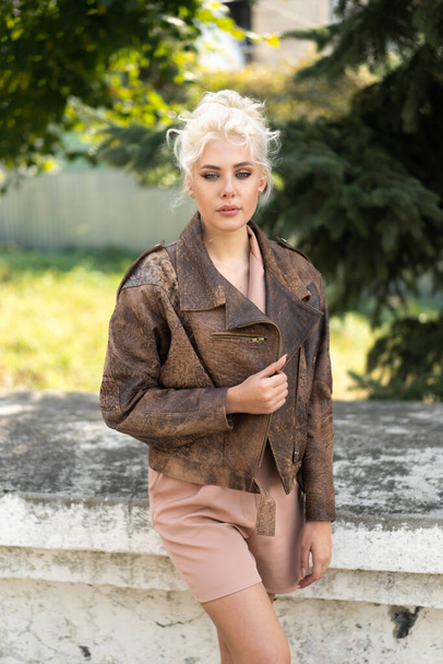 Blonde girl in romper and leather jacket posing on street - Foto, Imagen