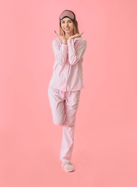 Portrait of woman in pajamas and with sleep mask on color background - Фото, изображение