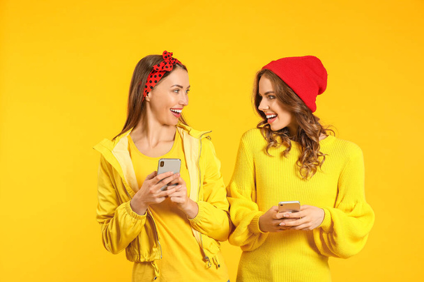 Young women with mobile phones on color background - Photo, Image
