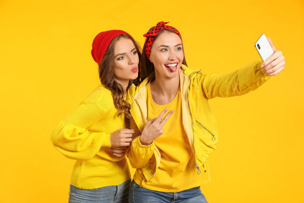Mujeres jóvenes tomando selfie sobre fondo de color
 - Foto, imagen