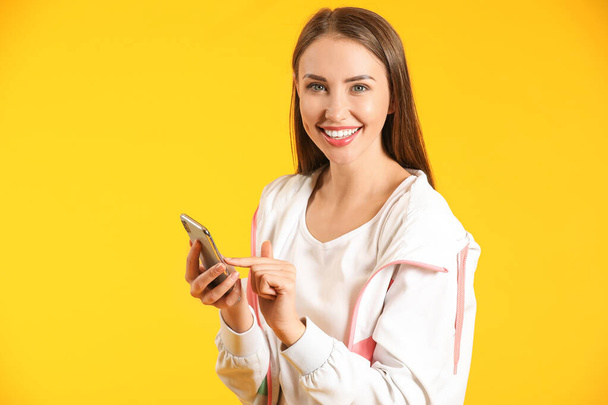 Mujer joven con teléfono móvil sobre fondo de color - Foto, Imagen