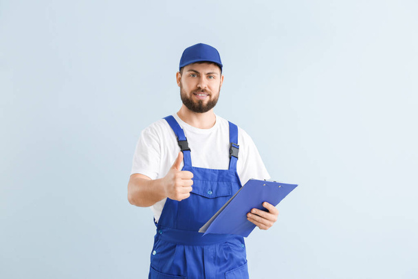 Handsome plumber showing thumb-up on color background - Photo, Image