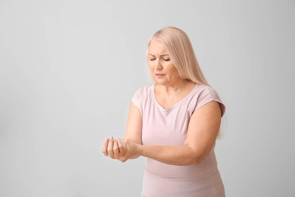 Starší žena trpící Parkinsonovým syndromem na šedém pozadí - Fotografie, Obrázek