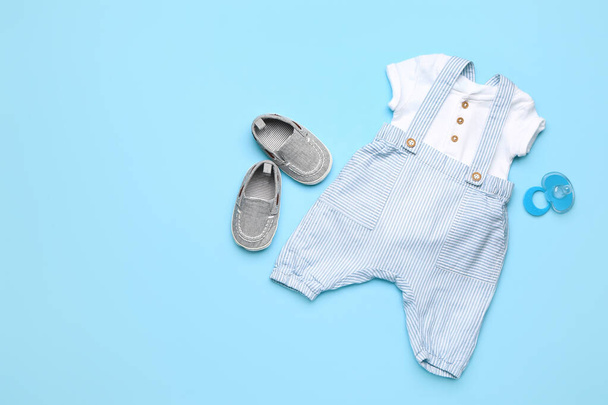 Baby clothes with booties and pacifier on color background - Φωτογραφία, εικόνα