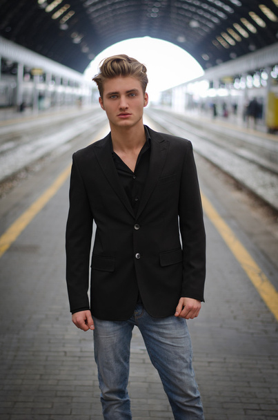 Attractive blue eyed, blond young man standing inside train station - Foto, Imagen