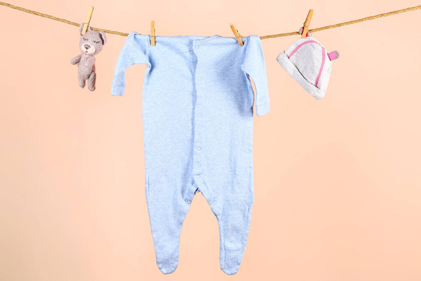 赤ちゃんの服やアクセサリーは、色の背景にロープにぶら下がっている - 写真・画像