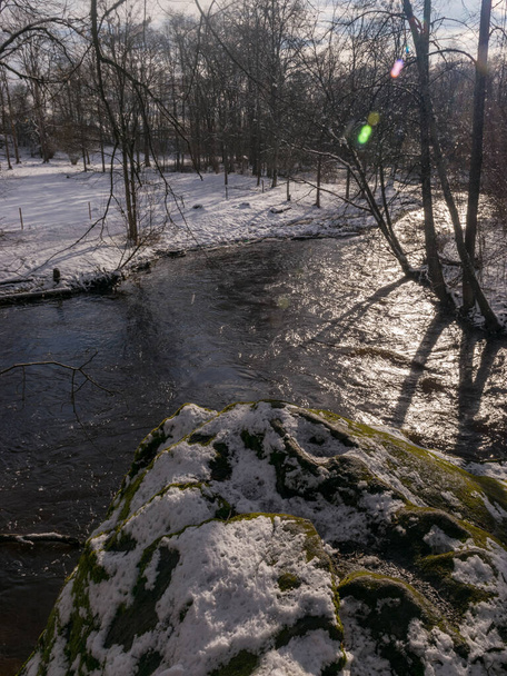 川の流れが速い冬の風景雪に覆われた土地低木や枝がたくさんあります - 写真・画像