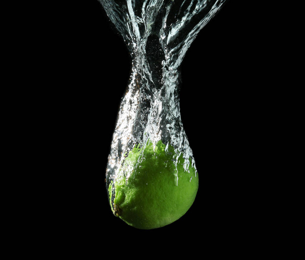 Falling of lime into water against dark background - Foto, Bild