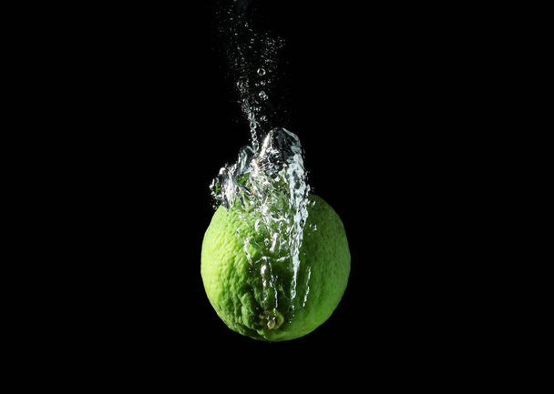 Falling of lime into water against dark background - Фото, изображение