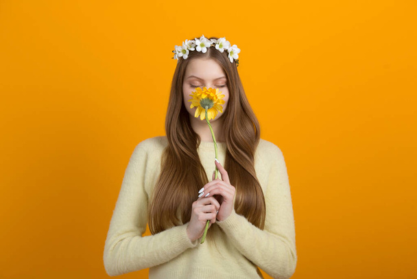 beautiful young woman with a wreath on her head on a yellow background - Foto, Imagen