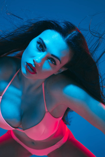 Modelo morena atraente no fundo do estúdio azul em luz de néon
 - Foto, Imagem