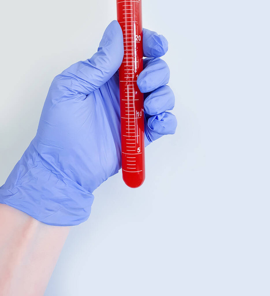 mão em uma luva médica mantém um tubo de teste com sangue
 - Foto, Imagem