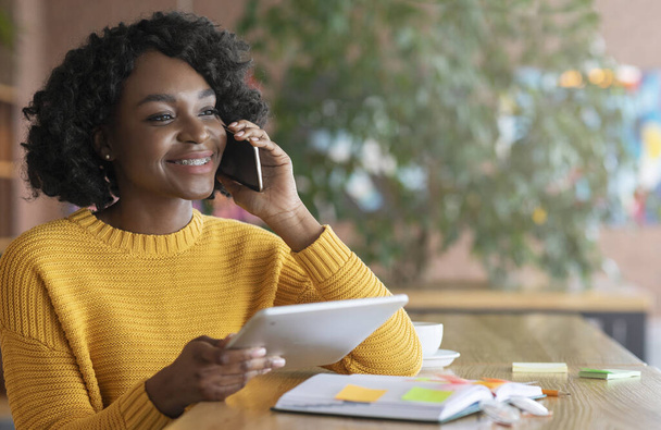 Enthousiaste afro femme d'affaires parlant au client au téléphone
 - Photo, image