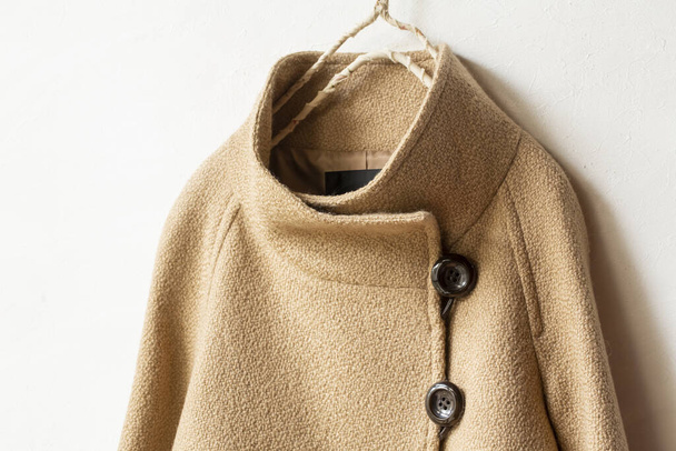 beige wool coat hanging on clothes hanger on white background.Close up. - Zdjęcie, obraz