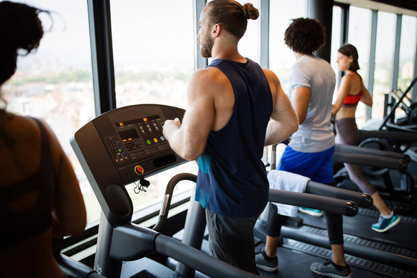 Group of young people running on treadmills in modern sport gym - Foto, imagen