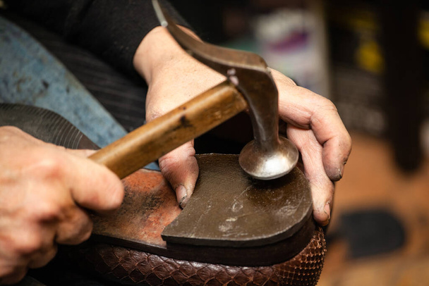 close-up of hands male shoemaker repairing shoes by nailing a heel - Photo, Image