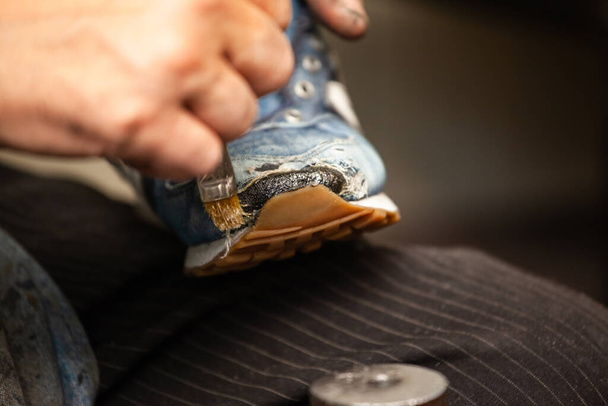 крупним планом чоловічого взуття, що склеює підошву взуття
 - Фото, зображення