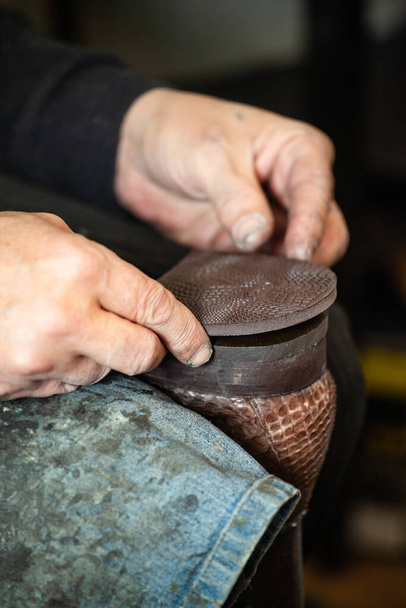 fechar as mãos de um homem a reparar sapatos
 - Foto, Imagem