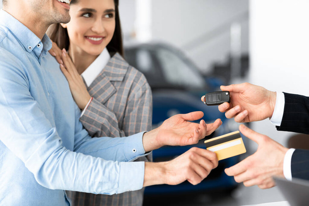 Para kupujących samochód dając sprzedawcy kartę kredytową w biurze sprzedaży - Zdjęcie, obraz