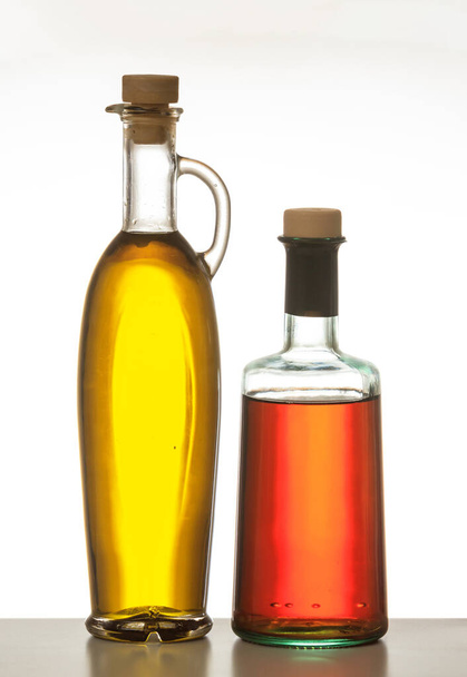 Olive oil and vinegar bottles isolated. Transparent glass bottles with cork stopper isolated against white background. Extra virgin olive oil and red wine vinegar - Foto, afbeelding