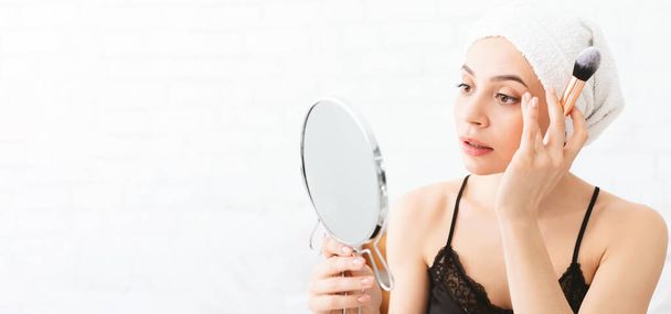 Mujer después de la ducha mirando el espejo con cepillo de maquillaje
 - Foto, imagen