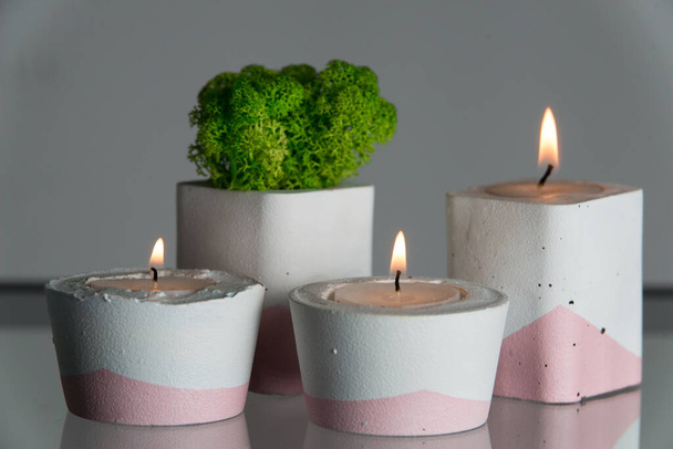kaarsen en mos in wit en roze betonnen kandelaars. - Foto, afbeelding