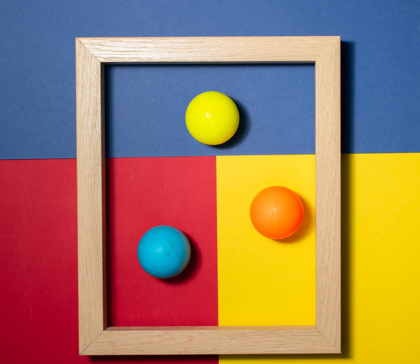 Wooden frame with colored balls inside, on a multi colored background. Space for copy-paste. Top view of a rectangular frame - Photo, Image