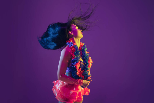 Attractive hawaiian brunette model on purple studio background in neon light - 写真・画像