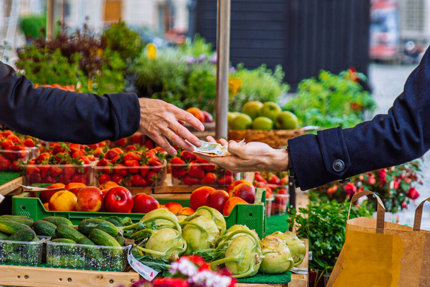 Yerel çiftçi pazarında sebze ve meyve için nakit ödeme yapan eller kapanır. - Fotoğraf, Görsel