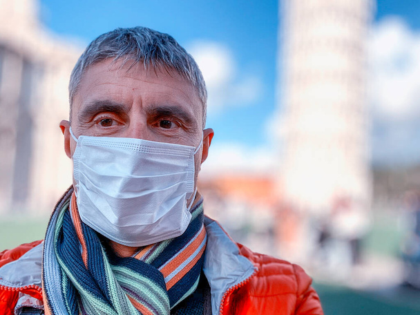 Coronavirus Covid-19 is spreading across Italy and Europe. Man visiting city landmark wearing protective face mask to avoid contagion outbreak. - Photo, Image