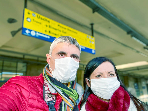 Coronavirus Covid-19 is spreading across Italy and Europe. Couple at the train station wearing protective face mask to avoid contagion outbreak. - Photo, Image