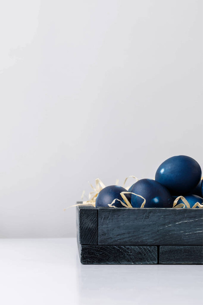 Huevos de Pascua azules en caja de madera sobre superficie blanca aislada en gris
 - Vector, Imagen