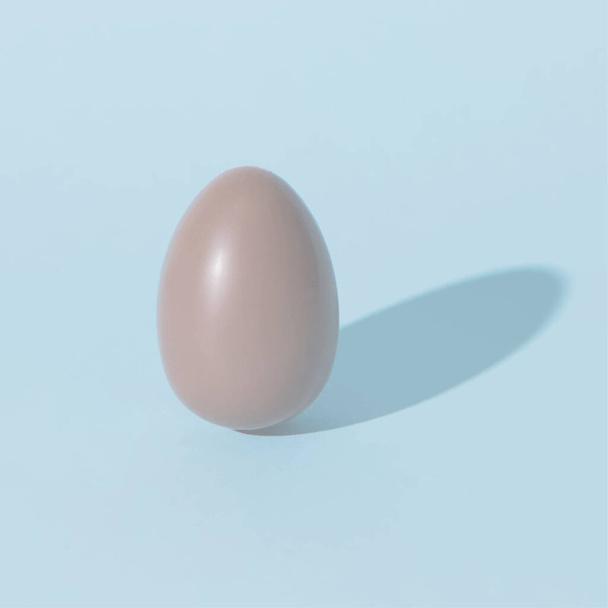 huevo de chocolate sobre fondo azul pálido con sombra
 - Vector, Imagen