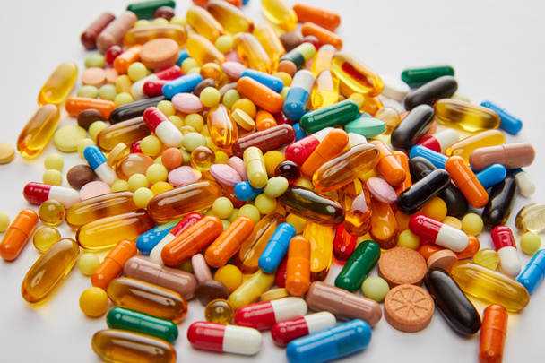 Foco seletivo de cápsulas e pílulas multicoloridas brilhantes no fundo branco
 - Foto, Imagem