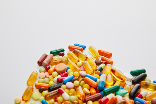 Hoge hoek uitzicht op heldere capsules en pillen op witte achtergrond - Foto, afbeelding