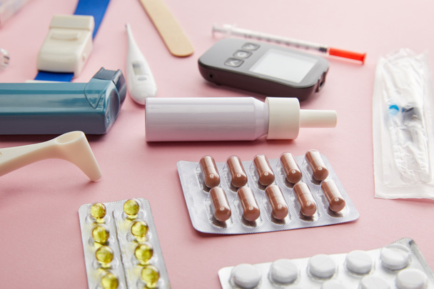 Foco seletivo de cápsulas, pílulas e objetos médicos em fundo rosa
 - Foto, Imagem