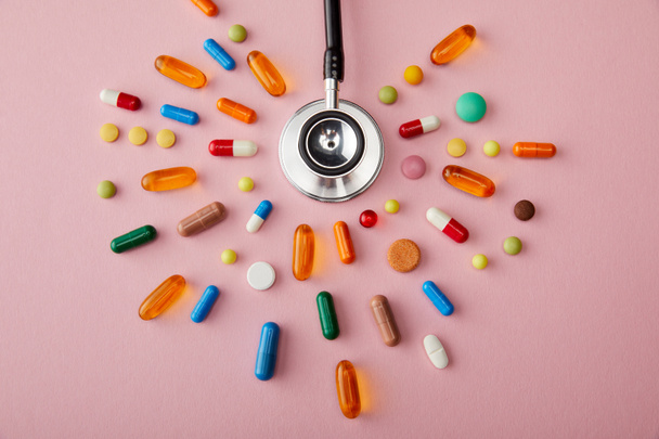 Top näkymä stetoskooppi kirkkaan värikäs pillereitä vaaleanpunainen tausta
 - Valokuva, kuva